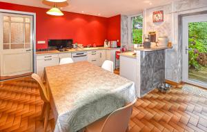 Lalevade-dʼArdècheにあるMaison En Pierresの赤い壁のキッチン(テーブル、椅子付)