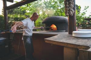 a man is standing in front of a pizza oven at HolaCamp Sitges Garrofer in Sitges