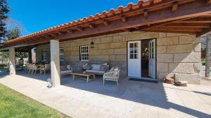 eine überdachte Terrasse mit einem Sofa und einem Tisch in der Unterkunft Quinta de Grejufe - Ponte de Lima in Olheiro