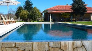 einen Pool mit blauem Wasser vor einem Haus in der Unterkunft Quinta de Grejufe - Ponte de Lima in Olheiro