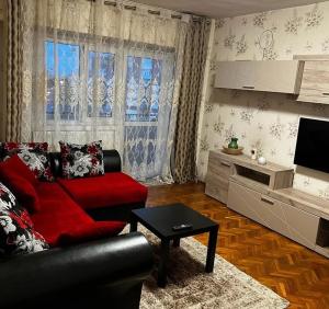 a living room with a red couch and a tv at Bros Apartment in Buzau