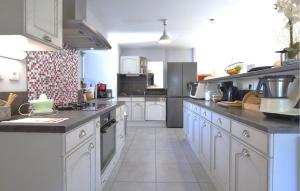 Bricqueville-sur-MerにあるMaison Spacieuse Littoralの白いキャビネットと家電製品を備えた広いキッチン