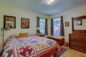 a bedroom with a bed and a dresser and windows at Living Color Cottage in Hood River