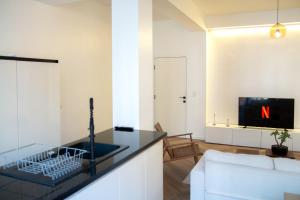 ein Wohnzimmer mit Fernseher und weißem Sofa in der Unterkunft Brussels South - Cosy Appartment in Brüssel + 7 Fotos