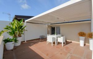 eine Terrasse mit Markise, Tischen und Topfpflanzen in der Unterkunft Cozy Apartment In Marina Di Ragusa With Wifi in Marina di Ragusa