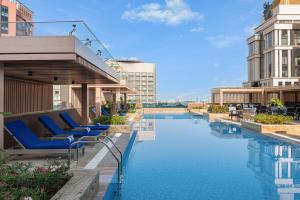 a hotel pool with blue lounge chairs and buildings at Marriott Executive Apartments Bengaluru UB City in Bengaluru