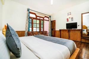 a bedroom with a large bed and a television at Ramta Jogi Hotel & Stays in Manāli
