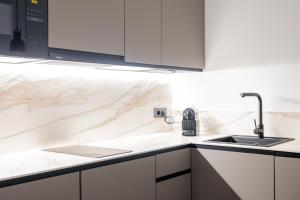 una cocina blanca con fregadero y armarios blancos en Guastavino by Alma Suites, en Valencia