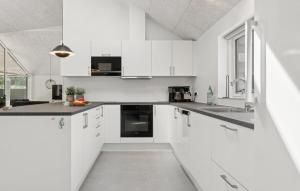 a white kitchen with white cabinets and black appliances at Cozy Home In Glesborg With Sauna in Fjellerup