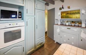 eine Küche mit weißen Schränken und einer Mikrowelle in der Unterkunft Maison Avec Piscine Privative in Rochegude