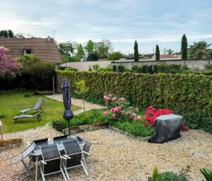 a garden with two chairs and an umbrella and flowers at La Suite 81 in Yzeure