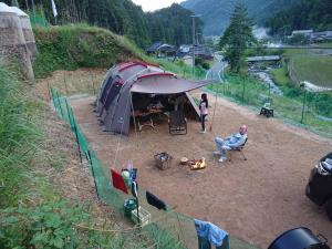 Un uomo e una donna in piedi accanto a una tenda di しっぽのそよ風 a Shiso