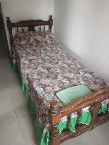 a wooden bed with a floral quilt on it at Areco en lo de Mabel in San Antonio de Areco