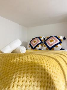 Una cama con manta amarilla y almohadas. en Malvern Road Studios, en Londres