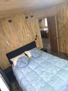 a bedroom with a large bed with two blue pillows at Cabaña La Casona in Chaitén