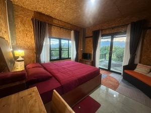 a bedroom with a red bed and a large window at Pharit guesthouse in Pai