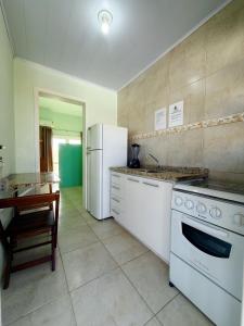 Una cocina con un refrigerador blanco y una mesa. en Pousada Lagoa dos Ventos, en Barra de Ibiraquera
