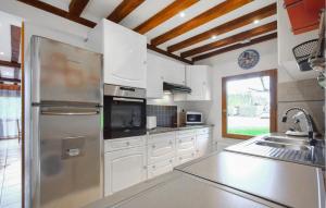 eine Küche mit weißen Schränken und einem Edelstahlkühlschrank in der Unterkunft Confortable Maison Normande in Saint-Léger-sur-Bonneville