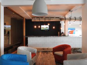a lobby with two chairs and a tv on a wall at Riotel Perce in Perce