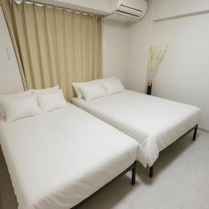 two beds sitting next to each other in a room at 1008 本町駅徒歩3分インペリアル快適ルーム 最大6名 in Osaka