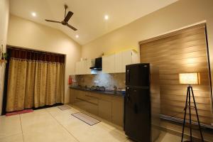 a kitchen with a black refrigerator and a ceiling fan at Sariska Bliss Farm, #2-BHK, #Private Pool & Garden in Alwar