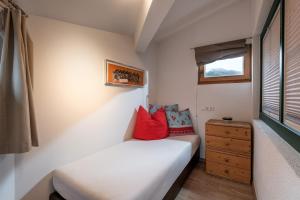 Hannes Appartement in im Zentrum von Kirchberg - by NV-Appartements في كيرشبرغ ان تيرول: غرفة نوم صغيرة مع سرير أبيض مع وسائد حمراء +صورتان