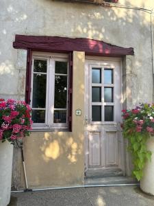 a door of a house with flowers in front of it at La Petite Maison mitoyenne in Condeissiat
