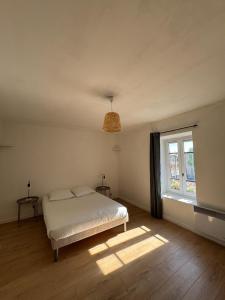 a white bedroom with a bed and a window at La Petite Maison mitoyenne in Condeissiat