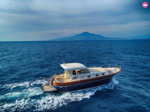 una barca in acqua con una montagna sullo sfondo di Capri Charter a Nerano