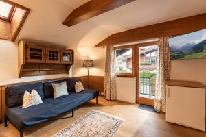 a living room with a blue couch and a large window at Petra in Kirchberg in Tirol