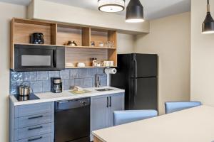 a kitchen with a black refrigerator and a counter at Candlewood Suites Victoria by IHG in Victoria +41 photos