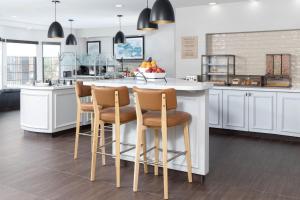 a kitchen with white cabinets and a island with bar stools at Staybridge Suites Chandler by IHG in Chandler