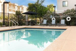 a swimming pool with chairs and an umbrella at Staybridge Suites Chandler by IHG in Chandler