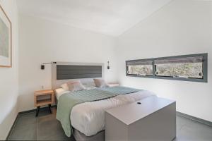 a white bedroom with a bed and two windows at Villa Comfort | 6 Pers. (Villa 56) in Ouddorp