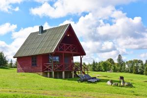 a red building on top of a hill with a bench at LAKE VIEW Resort - Sodyba in Skirlėnai