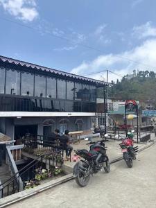 dos motocicletas estacionadas frente a un edificio en Abhyasi Hotel De Cafe, en Suryodaya