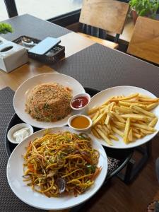 una mesa con dos platos de comida y papas fritas en Abhyasi Hotel De Cafe, en Suryodaya