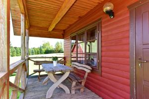 SkirlėnaiLAKE VIEW Resort - Sodyba的木制门廊上摆放着一张木桌和一张野餐桌 更多25张照片