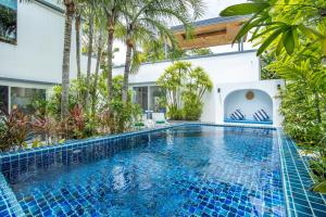 an infinity pool in a villa with palm trees at Villa Guenlaur 3 studios with kitchenette and pool in Ban Saiyuan (1)