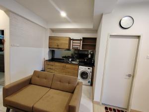 a living room with a couch and a clock on the wall at Timurbay Seafront By Moonlight pool view in Kuantan