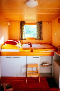 a small bedroom with a bed and a desk with a stool at Off-grid maringotka Cibéba in Rača