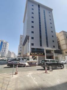 a large building with cars parked in front of it at فندق فجر الرسالة in Al ‘Azīzīyah