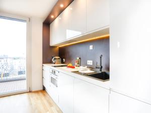 a kitchen with white cabinets and a large window at Penthouse Studio with Terrace and City View - 5 mins walk to Hauptbahnhof Train Station in Vienna