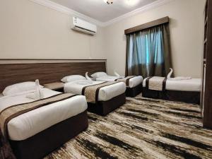 a group of four beds in a hotel room at فندق فجر الرسالة in Al ‘Azīzīyah