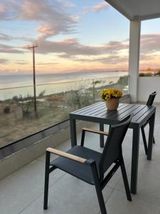 a table and chair on a balcony with a view of the ocean at Kyllini Seaside Apartments & Rooms in Kyllini