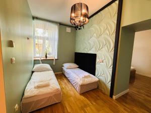 two beds in a room with a chandelier at Apartament R48 in Dąbrowa Tarnowska