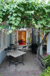 un patio con tavoli e sedie sotto un albero di Tintagel Guest House a Città del Capo