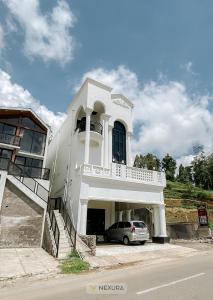 un bâtiment blanc avec une voiture garée devant dans l'établissement Grand House Nexura Collection, à Diyeng