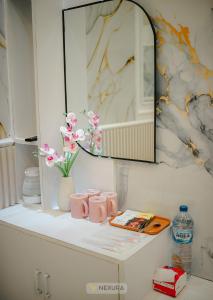 un comptoir blanc avec des tasses roses et des fleurs dessus dans l'établissement Grand House Nexura Collection, à Diyeng