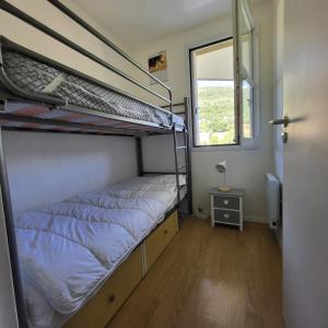 Un dormitorio con dos literas y una ventana. en Comfortable 30m balcony and mountain view, en Briançon